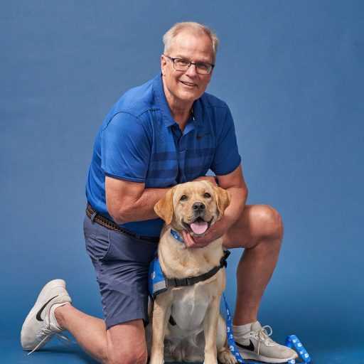 Bob Eike kneeling next to yellow labrador retriever